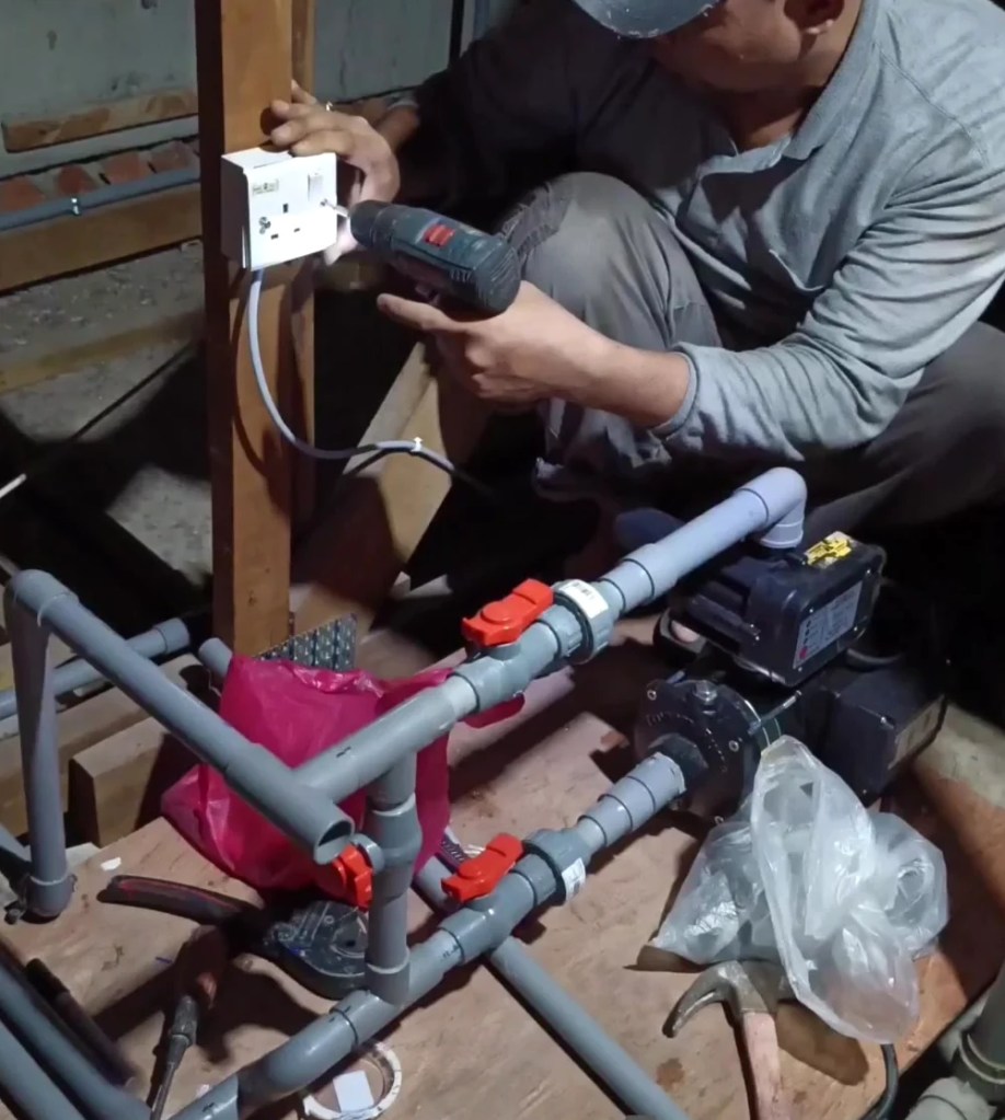 Kerja pemasangan sistem water pump dengan paip PVC dan injap di ruang loteng